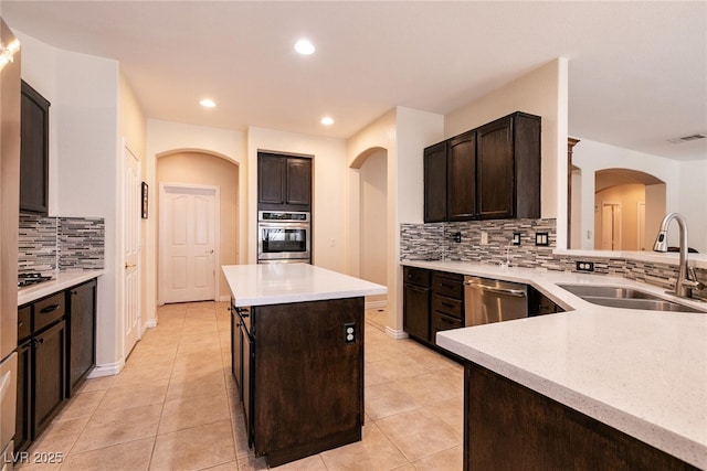 kitchen featuring visible vents, a center island, dark brown cabinetry, appliances with stainless steel finishes, and a sink