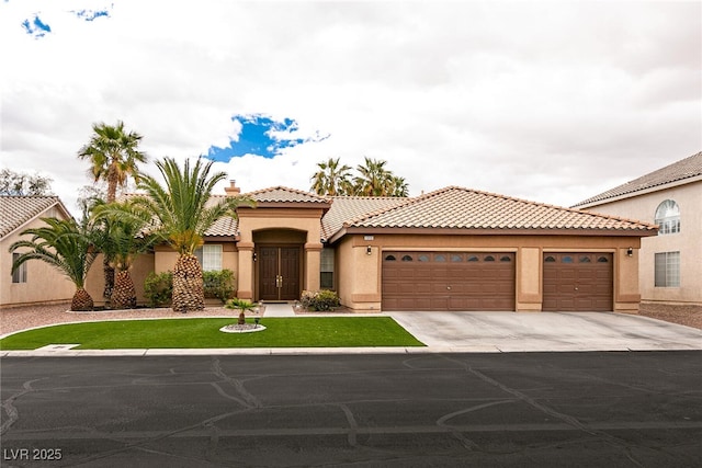 mediterranean / spanish home with stucco siding, driveway, a tile roof, and an attached garage