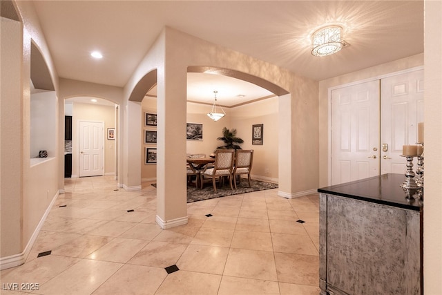 entrance foyer with light tile patterned floors, baseboards, arched walkways, and recessed lighting