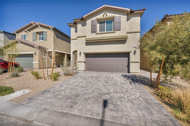 mediterranean / spanish home with a tiled roof, decorative driveway, an attached garage, and stucco siding