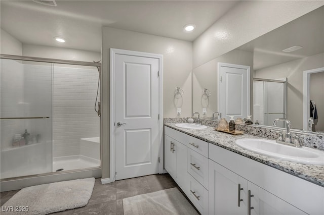 full bath with a sink, a stall shower, and double vanity