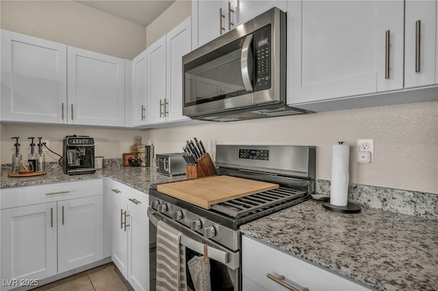 kitchen with light stone counters, stainless steel appliances, and white cabinets