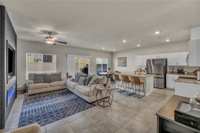 living area featuring light tile patterned flooring, visible vents, recessed lighting, and a ceiling fan