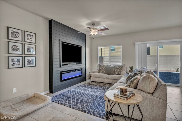 tiled living room with visible vents, a large fireplace, and ceiling fan