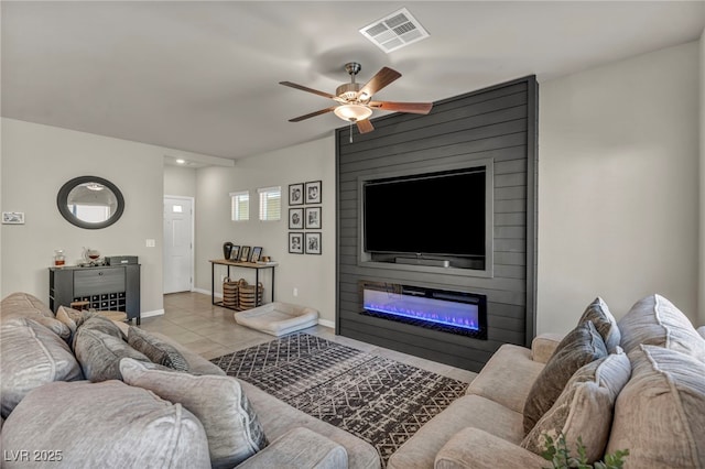 tiled living room with a fireplace, a ceiling fan, visible vents, and baseboards