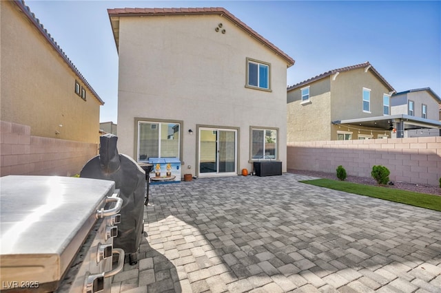 rear view of house with stucco siding, a patio, and fence