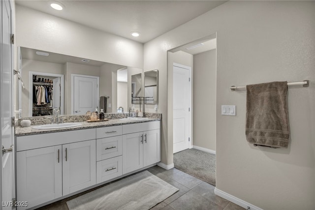 full bathroom with a sink, baseboards, a spacious closet, and double vanity