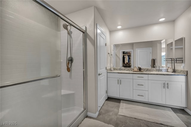 bathroom with recessed lighting, a sink, a shower stall, and double vanity