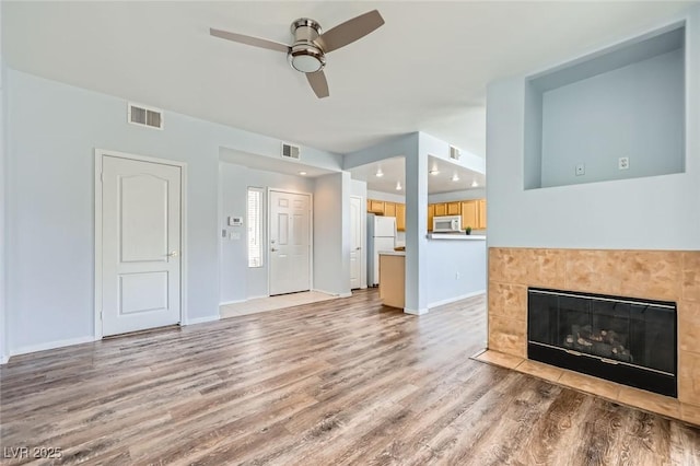 unfurnished living room with light wood finished floors, visible vents, baseboards, and a ceiling fan