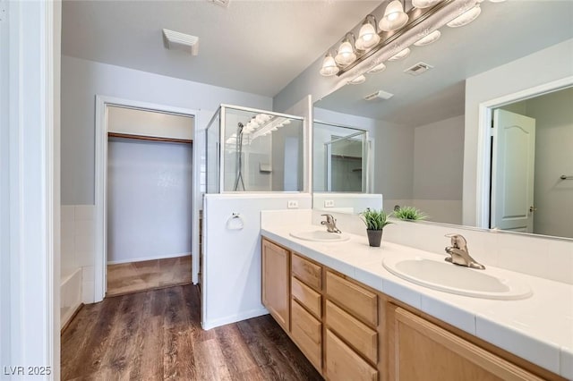 bathroom featuring visible vents, a shower stall, wood finished floors, and a sink