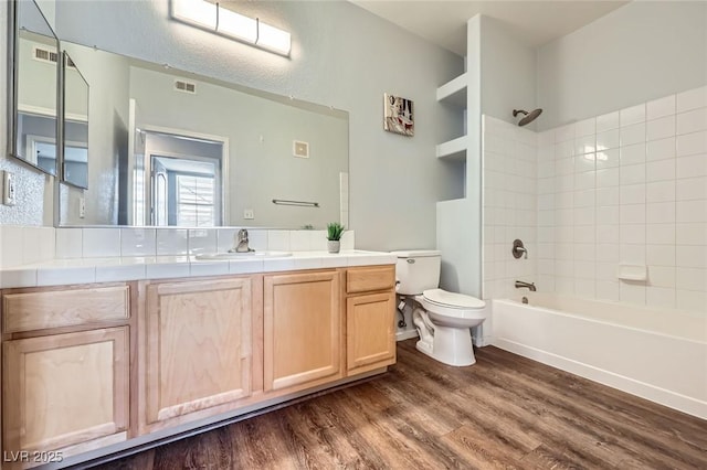 full bath featuring visible vents, toilet, bathing tub / shower combination, wood finished floors, and vanity