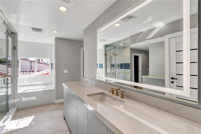 full bath with vanity, a shower stall, wood finished floors, and visible vents