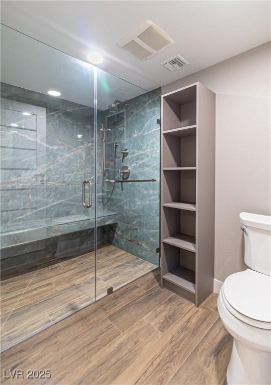 full bathroom with a stall shower, visible vents, toilet, and wood finished floors