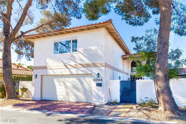 view of front of property featuring stucco siding, a gate, a tile roof, fence, and an attached garage