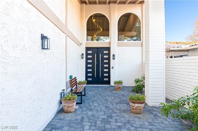 property entrance featuring stucco siding and fence