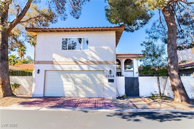 mediterranean / spanish-style house featuring fence, a garage, and stucco siding