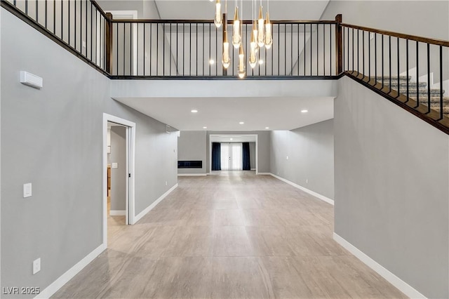 interior space with a notable chandelier, a high ceiling, stairs, and baseboards