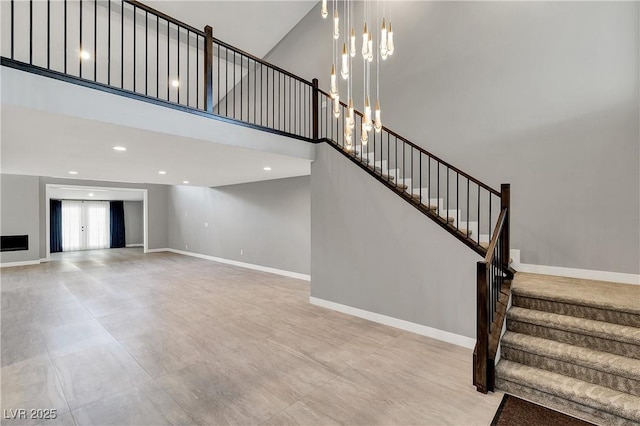 staircase featuring recessed lighting, baseboards, and a high ceiling