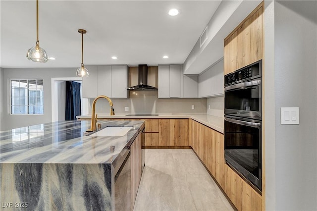 kitchen with visible vents, a sink, double oven, wall chimney range hood, and modern cabinets