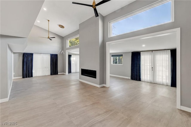 unfurnished living room with baseboards, high vaulted ceiling, a fireplace, and a ceiling fan