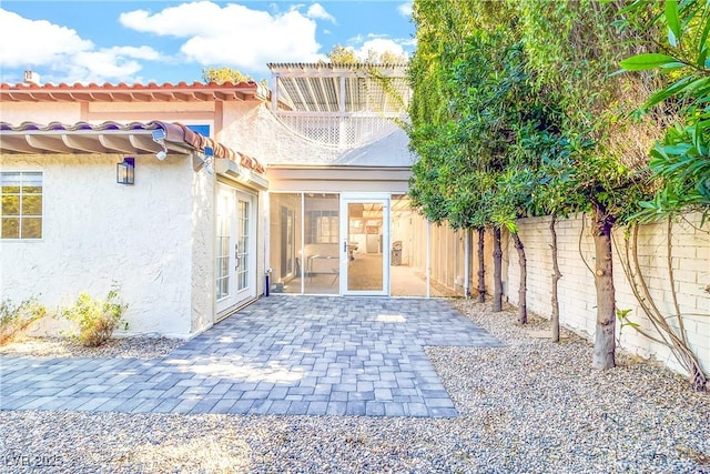 exterior space with a fenced backyard, stucco siding, french doors, a tile roof, and a patio area