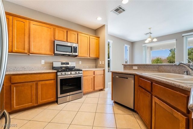 kitchen with light tile patterned floors, visible vents, a sink, stainless steel appliances, and brown cabinets