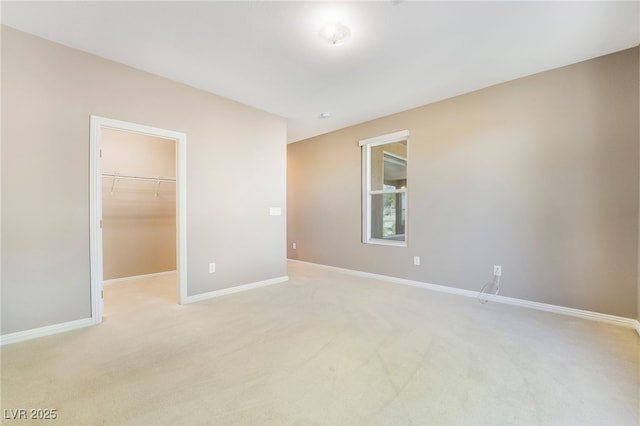 unfurnished bedroom featuring a spacious closet, light colored carpet, a closet, and baseboards