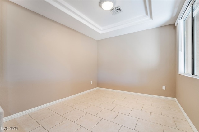 empty room featuring visible vents, baseboards, a raised ceiling, and light tile patterned flooring