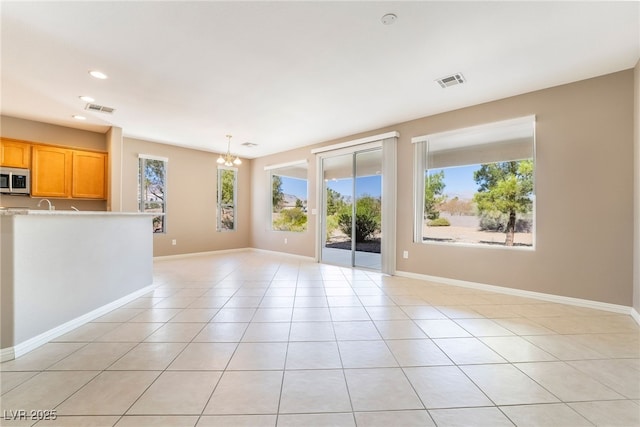 unfurnished living room featuring light tile patterned floors, visible vents, baseboards, and an inviting chandelier