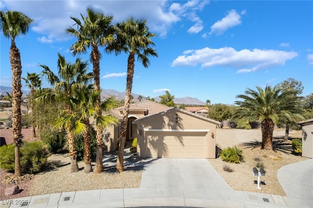 view of front of home with driveway, an attached garage, stucco siding, a tile roof, and a mountain view