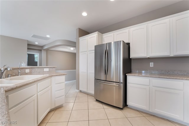 4963 Pensier St, Las Vegas, NV 89135 - kitchen with freestanding refrigerator, light tile patterned floors, a sink, white cabinetry, and arched walkways