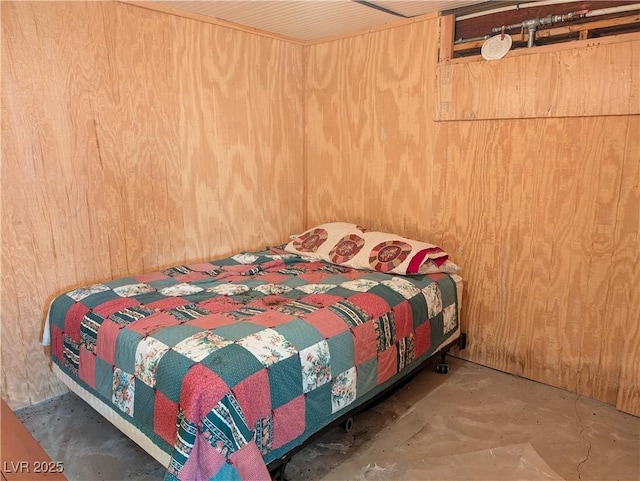 bedroom with wooden walls and concrete floors