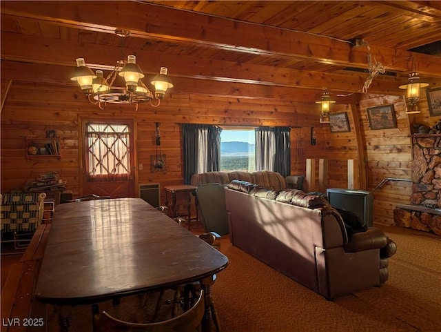 dining space featuring beam ceiling, carpet flooring, an inviting chandelier, and wooden walls