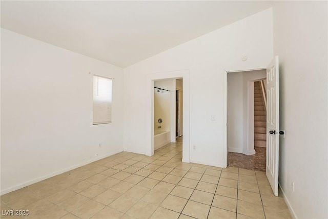 spare room featuring light tile patterned flooring and vaulted ceiling