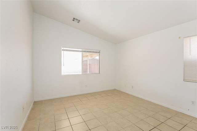 empty room featuring baseboards, visible vents, plenty of natural light, and lofted ceiling