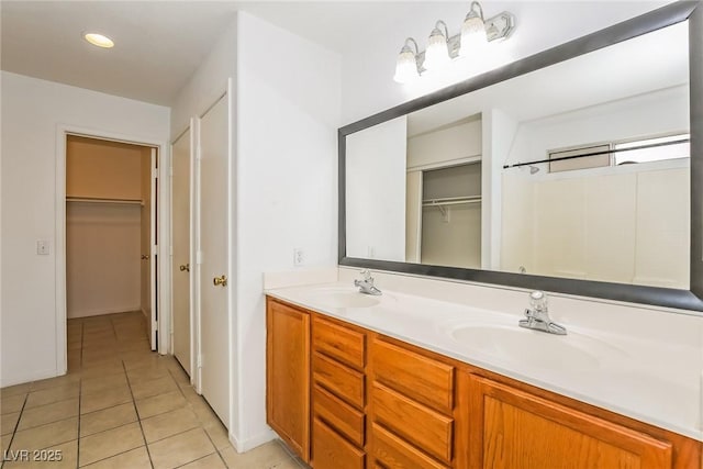 bathroom featuring tile patterned flooring, double vanity, a spacious closet, and a sink