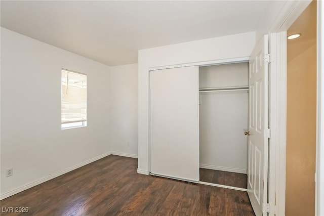 unfurnished bedroom featuring a closet, baseboards, and wood finished floors