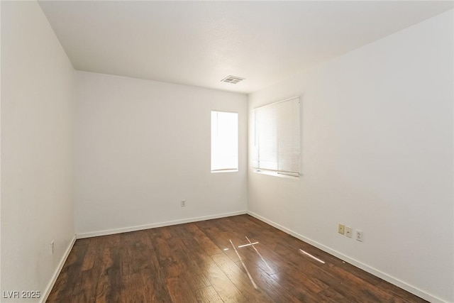 unfurnished room featuring visible vents, wood finished floors, and baseboards