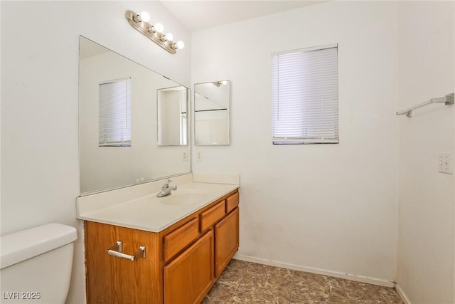 half bathroom with baseboards, toilet, and vanity