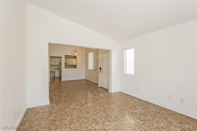 unfurnished room featuring lofted ceiling and baseboards