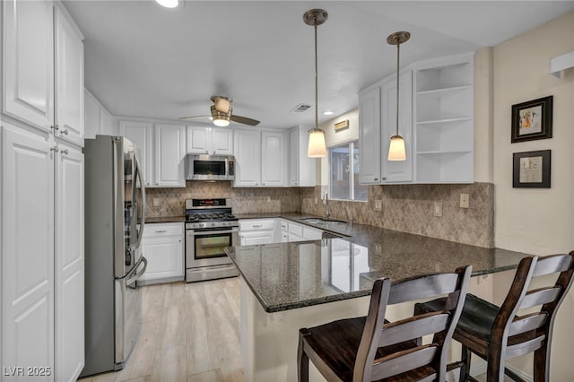 kitchen with white cabinets, appliances with stainless steel finishes, a peninsula, and a sink