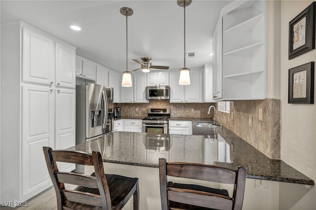 kitchen featuring a sink, backsplash, appliances with stainless steel finishes, a peninsula, and open shelves