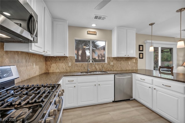 kitchen with dark stone countertops, visible vents, a sink, stainless steel appliances, and white cabinets