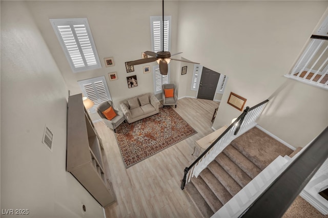 living room featuring a high ceiling, wood finished floors, baseboards, and ceiling fan