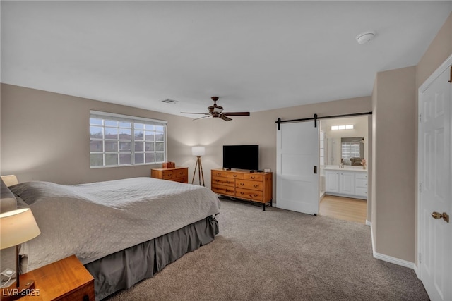 bedroom featuring visible vents, a ceiling fan, a barn door, carpet, and baseboards