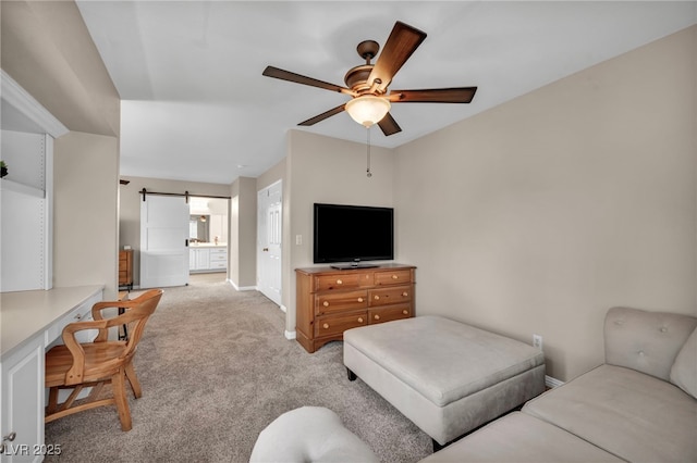 living area with a barn door, baseboards, light colored carpet, and ceiling fan