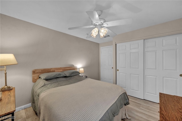 bedroom featuring visible vents, baseboards, ceiling fan, light wood-style flooring, and a closet