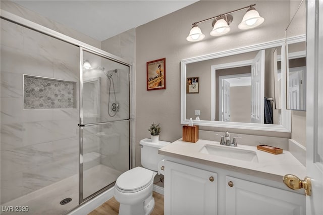 bathroom featuring toilet, a stall shower, vanity, and a textured wall