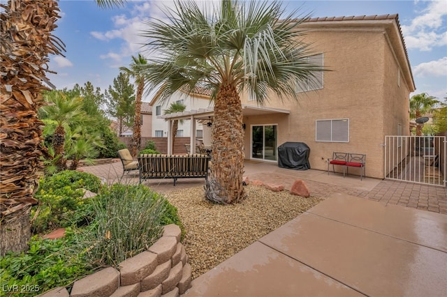 rear view of property with a patio, fence, and stucco siding