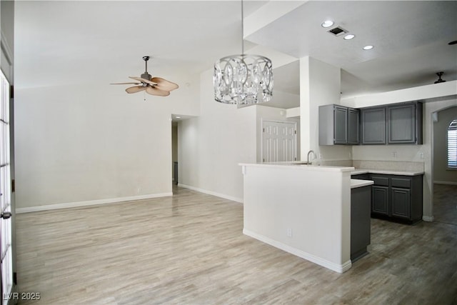 kitchen featuring light countertops, gray cabinets, ceiling fan with notable chandelier, and light wood-type flooring